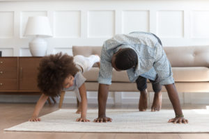 African father and little daughter do push-up exercise indoors
